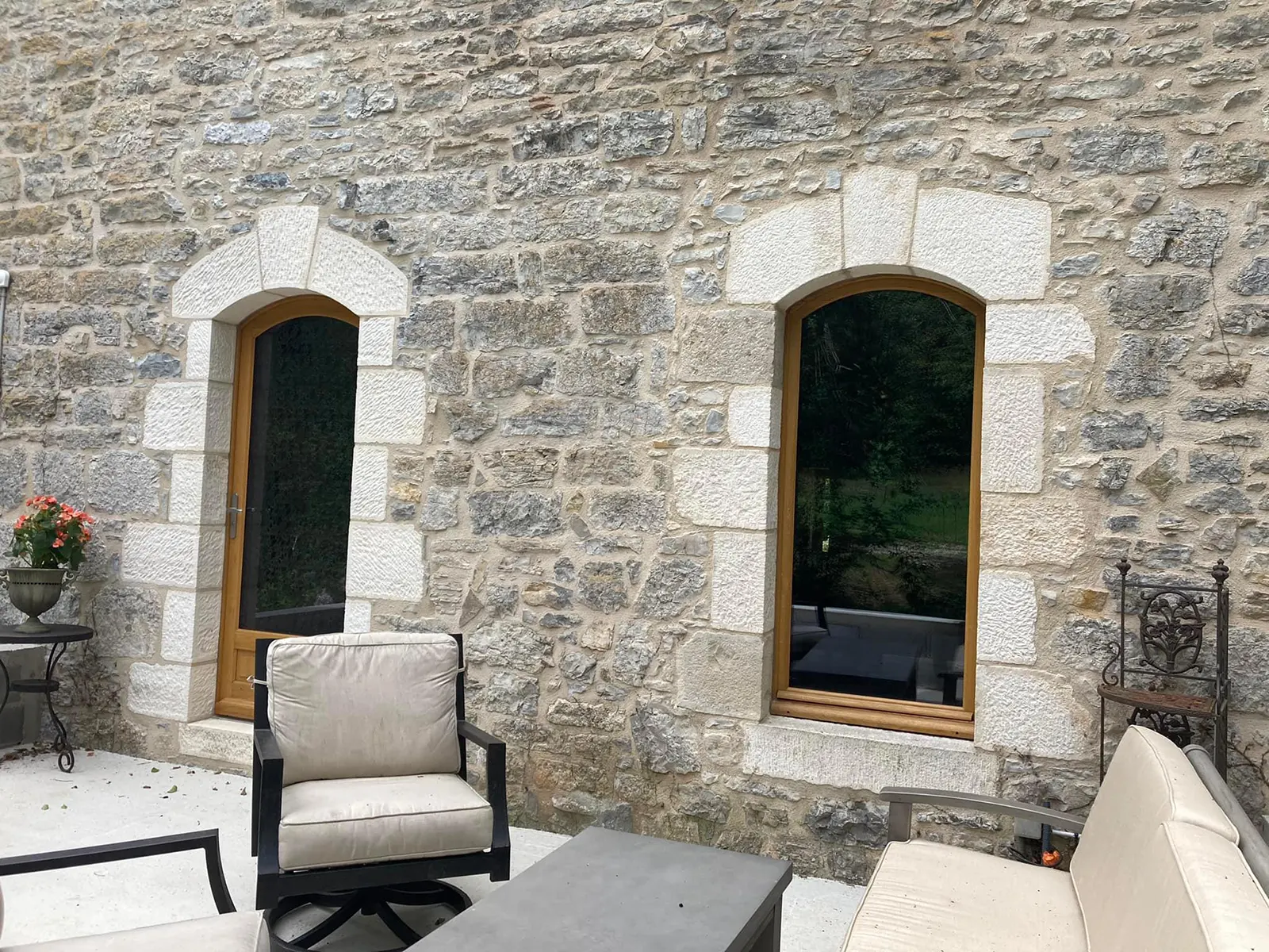 Fa&ccedil;ade maison en pierre avec fen&ecirc;tres cintr&eacute;es bois r&eacute;novation ouverture traditionnelle terrasse ext&eacute;rieure am&eacute;nagement charme ancien